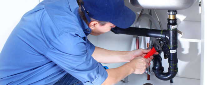 plumber repairing drain under sink